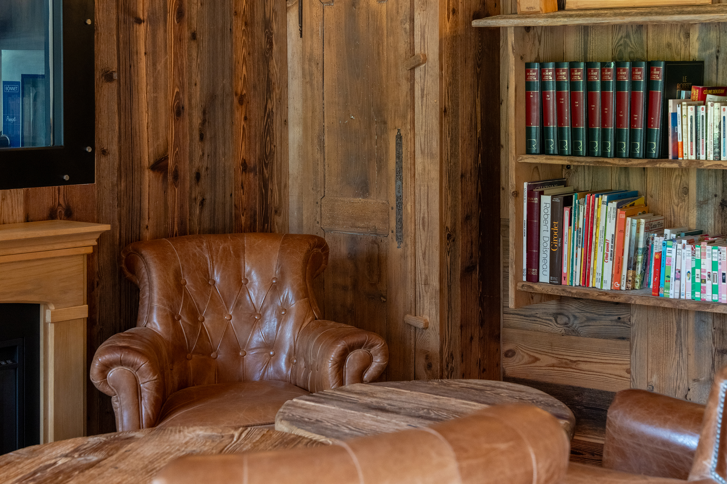 détail du lounge du tillau, avec un fauteuil, table et bibliothèque en arrière plan